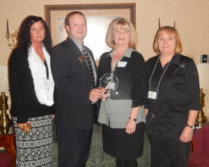 David Hill, Chamber President, presents Tina Hughes, Denise Christescu, and Christine Ferraro with Westbrook Village Apts./K&D with their award.